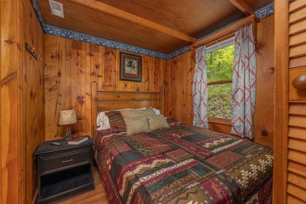 Bedroom with a bed, night stand, and lamp at Heavenly Hideaway, a 2-bedroom cabin rental located in Gatlinburg