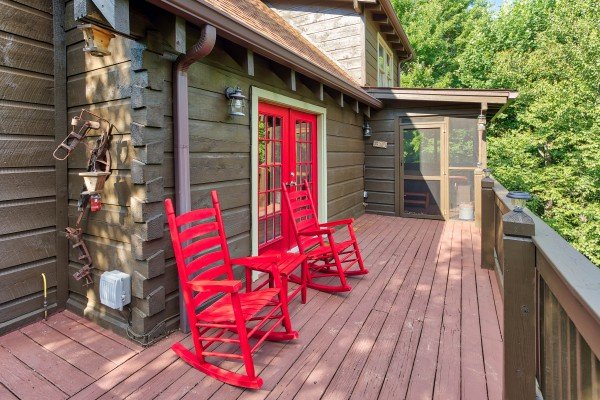 Red rocking chairs on the deck at Wonders in the Sky, a 3 bedroom cabin rental located in Gatlinburg
