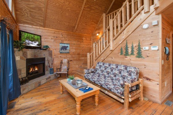 Fireplace, TV, and futon in the living room at My Blue Heaven, a 1 bedroom cabin rental located in Gatlinburg