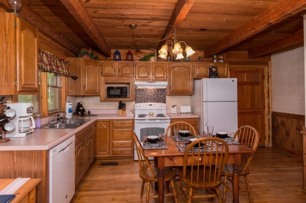 Kitchen with white appliances and dining space for 4 at Little Bear, a 1 bedroom cabin rental located in Pigeon Forge