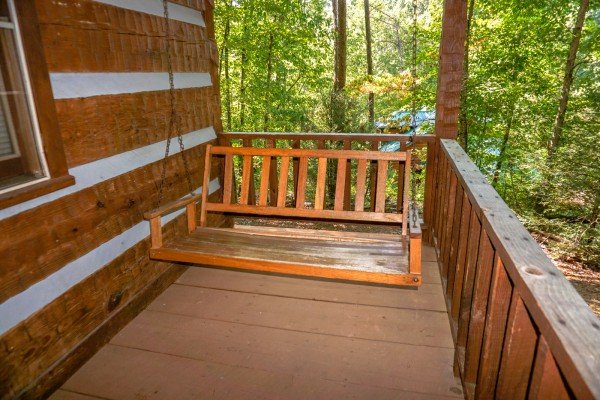A closer look at the porch swing on the covered deck surrounded by woods at Little Bear, a 1 bedroom cabin rental located in Pigeon Forge