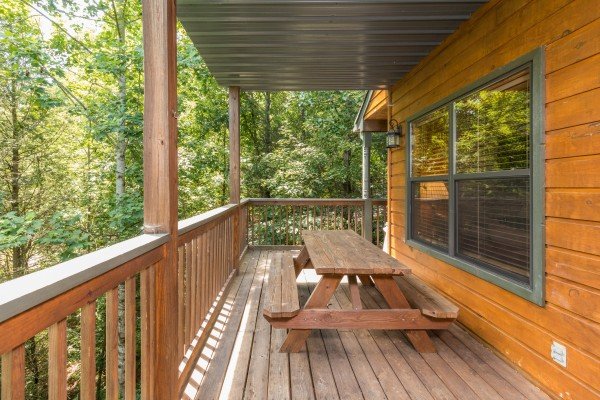 Picnic table on a covered deck at Stones Throw, a 4 bedroom cabin rental located in Pigeon Forge