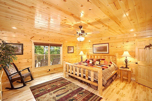 King sized log bed in the main level bedroom at Incredible! A 6 bedroom cabin rental located in Gatlinburg
