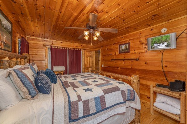 Bedroom with log bed, tv, and patio entrance at Tip Top View, a 3 bedroom cabin rental located in Pigeon Forge