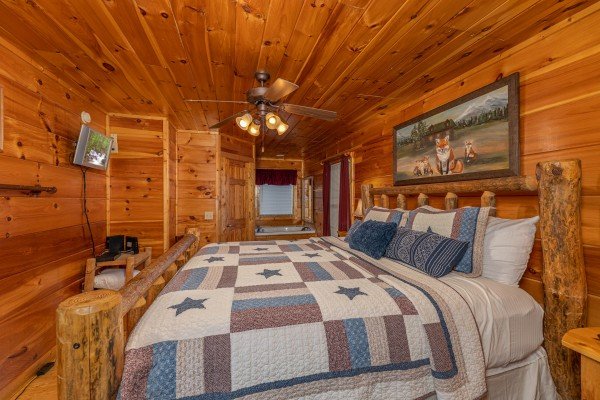 Log bed with TV and nightstand at Tip Top View, a 3 bedroom cabin rental located in Pigeon Forge