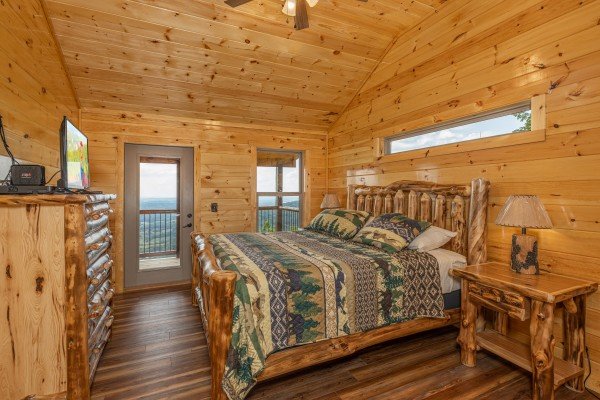 Bedroom with a log bed, dresser, TV, and deck access at 4 States View, a 2 bedroom cabin rental located in Pigeon Forge