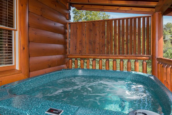 Hot tub on a covered deck with privacy fence at Bearfoot Memories, a 2-bedroom cabin rental located in Pigeon Forge