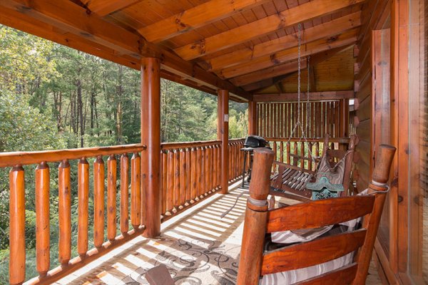 Covered deck with rocker, swing, and grill at Bearfoot Memories, a 2-bedroom cabin rental located in Pigeon Forge