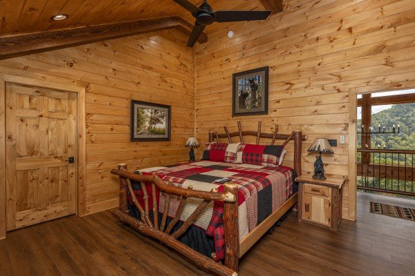 Bedroom with a king log bed, two night stands, and lamps at Black Bears & Biscuits Lodge, a 6 bedroom cabin rental located in Pigeon Forge