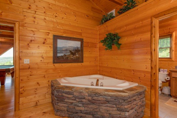 Corner jacuzzi with stone surround at Mountain Adventure, a 2 bedroom cabin rental located in Pigeon Forge