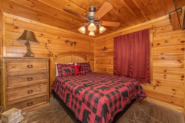 Bedroom with a queen bed, dresser, and lamp at King Wolf Lodge, a 3 bedroom cabin rental located in Pigeon Forge