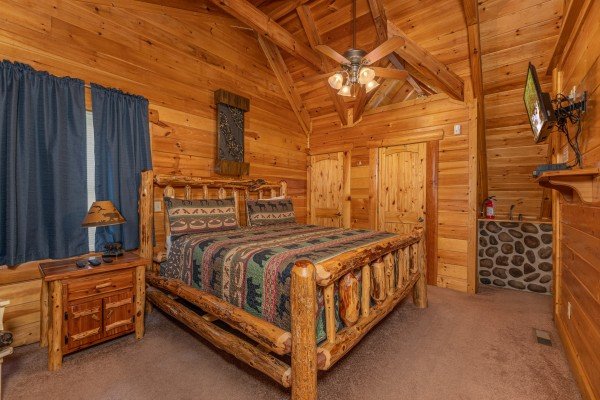 Bedroom with log bed, night stand, dresser, and TV at King Wolf Lodge, a 3 bedroom cabin rental located in Pigeon Forge