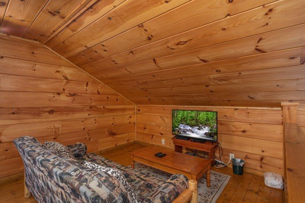Futon and TV in the loft space at Licklog Hollow, a 1 bedroom cabin rental located in Pigeon Forge