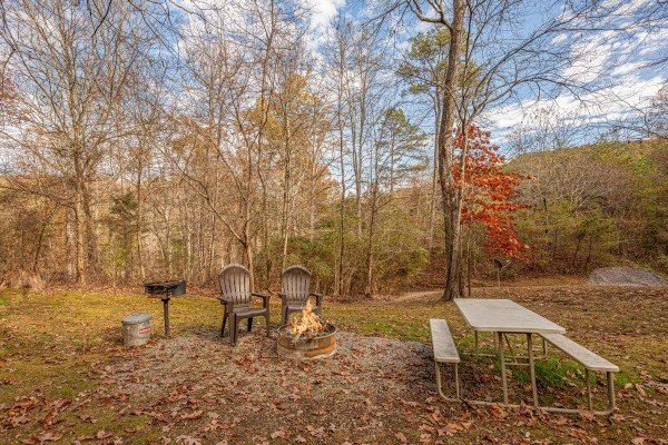 Charcoal grill, chairs, fire pit, and picnic table in the yard at Licklog Hollow, a 1 bedroom cabin rental located in Pigeon Forge