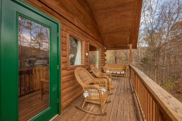 Deck with wicker rocking chairs and a swing at Licklog Hollow, a 1 bedroom cabin rental located in Pigeon Forge