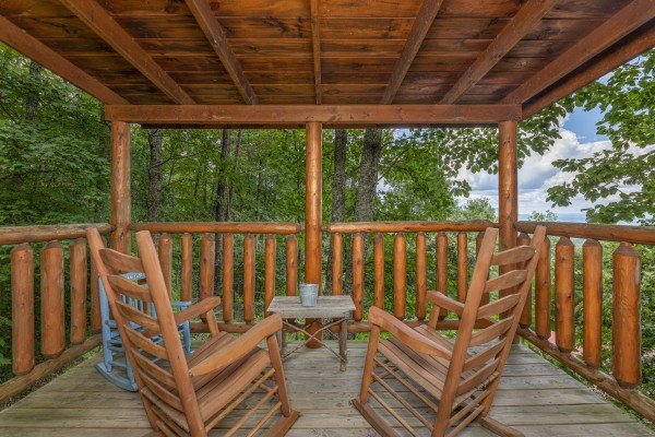 Rocking chairs and table on a deck at Bearway to Heaven, a 2 bedroom cabin rental located in Gatlinburg
