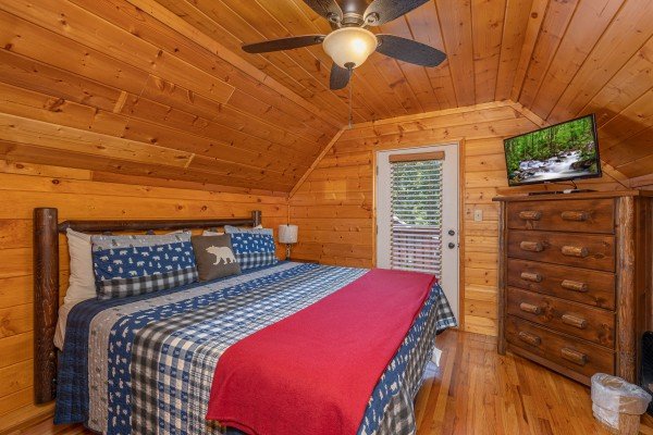 Bedroom with a king bed, dresser, TV, and deck access at Pool Side Lodge, a 6 bedroom cabin rental located in Pigeon Forge