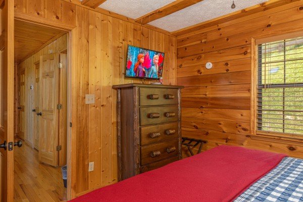 Dresser, TV, and luggage rack in a bedroom at Pool Side Lodge, a 6 bedroom cabin rental located in Pigeon Forge