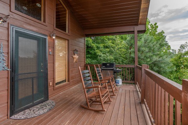 Front porch with rocking chairs and a gas grill at Into the Mist, a 3 bedroom cabin rental located in Pigeon Forge