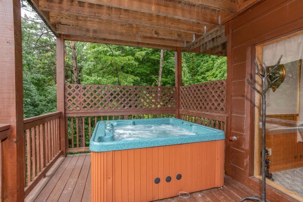 Hot tub on a covered deck with privacy lattice at Into the Mist, a 3 bedroom cabin rental located in Pigeon Forge