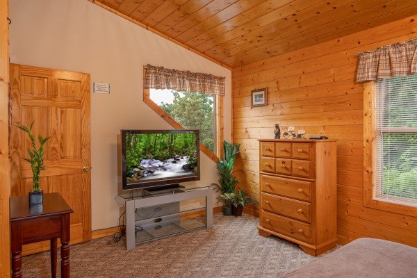 Bedroom with a chest of drawers, large TV, and natural light at Into the Mist, a 3 bedroom cabin rental located in Pigeon Forge