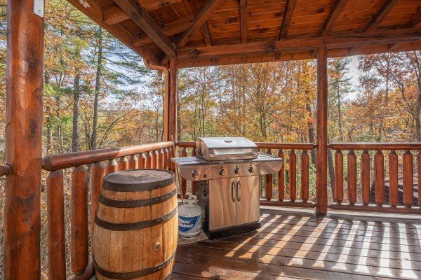 Grill and barrel table on a covered deck at All Hours, a 2 bedroom cabin rental located in Pigeon Forge