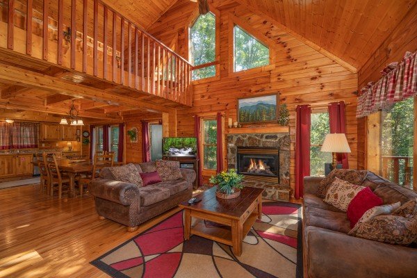 Vaulted living room with fireplace, TV, dining area, and kitchen at Majestic Mountain, a 4 bedroom cabin rental located in Pigeon Forge