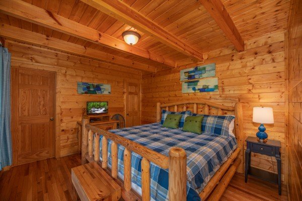 Log bed, night stand with lamp, and TV in a bedroom at Majestic Mountain, a 4 bedroom cabin rental located in Pigeon Forge