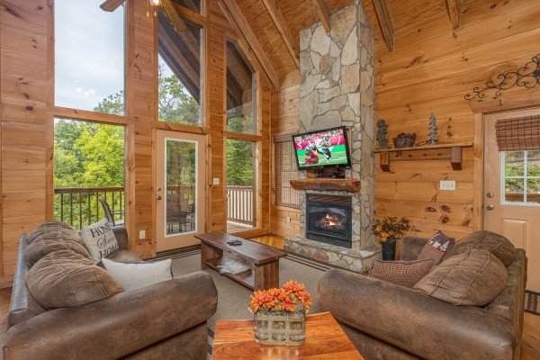 Living room with fireplace, TV, and deck access at Auburn Sky, a 4 bedroom cabin rental located in Pigeon Forge