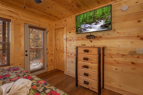 Dresser, TV, and deck access in a bedroom at Pinot Splash, a 4 bedroom cabin rental located in Gatlinburg
