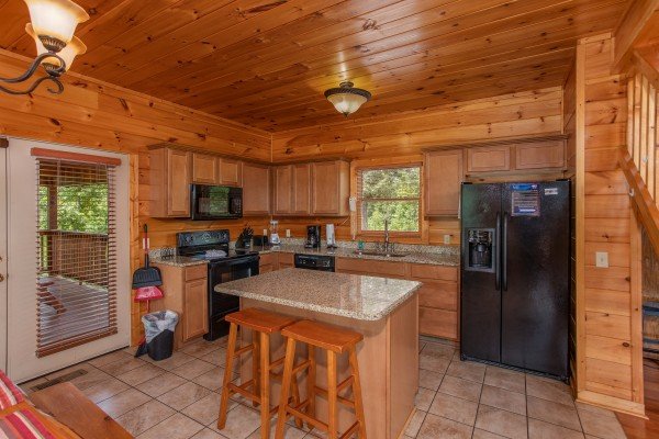 Kitchen with black appliances and an island and seating for two at Four Seasons Lodge, a 3-bedroom cabin rental located in Pigeon Forge