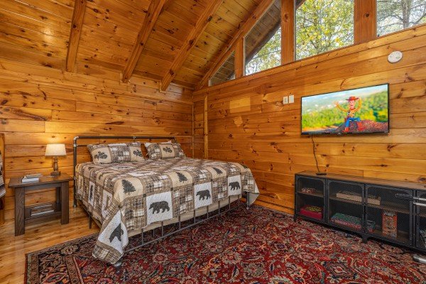 Bed in the loft with a table, lamp, and TV at Silver Creek Cabin, a 1 bedroom cabin rental located in Pigeon Forge